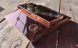Two polished copper-colored metal bars stacked on a weathered wooden surface, with engraved markings including '999 CU' 500g copper